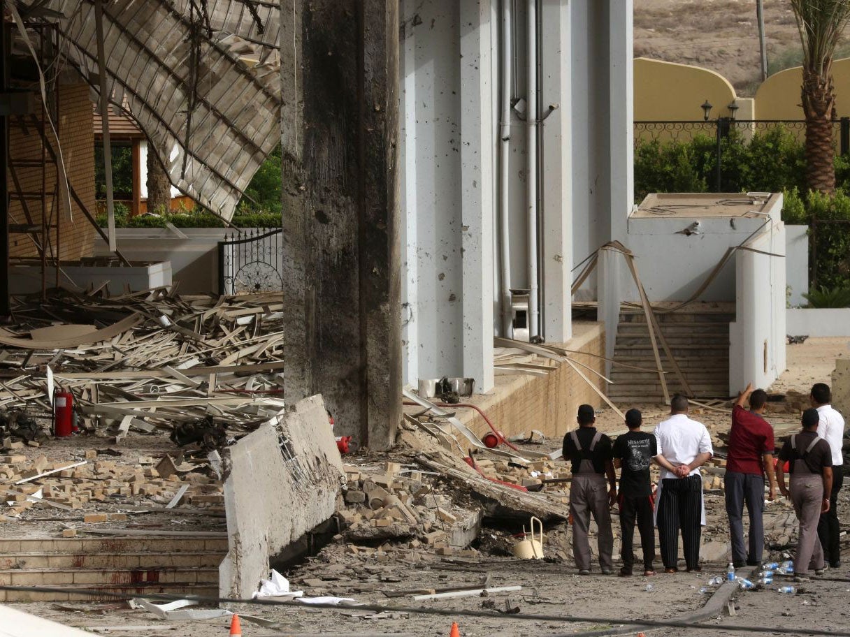 Civilians and security forces inspect the aftermath of the car bomb attack at the Babylon hotel