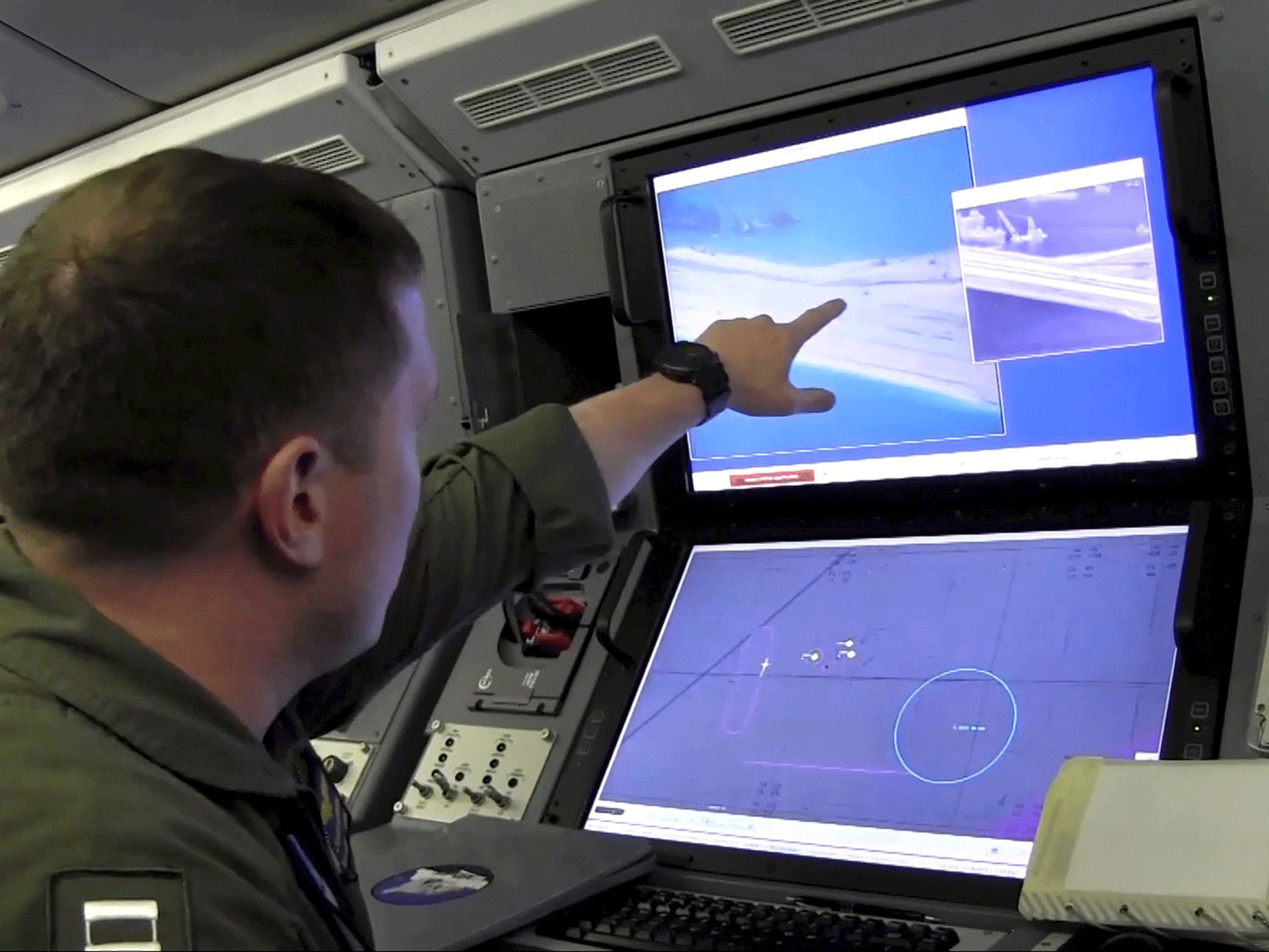 A U.S. Navy crewman aboard a surveillance aircraft views a screen purportedly showing Chinese construction in the South China Sea