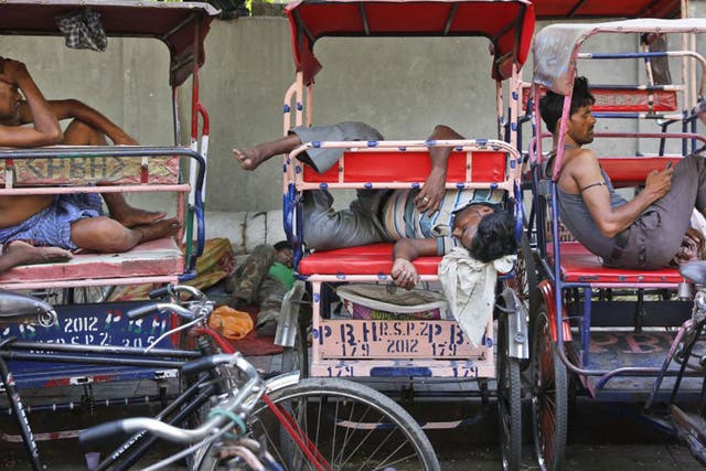 Rickshaw pullers sleep as they wait for the few customers venturing out in Delhi