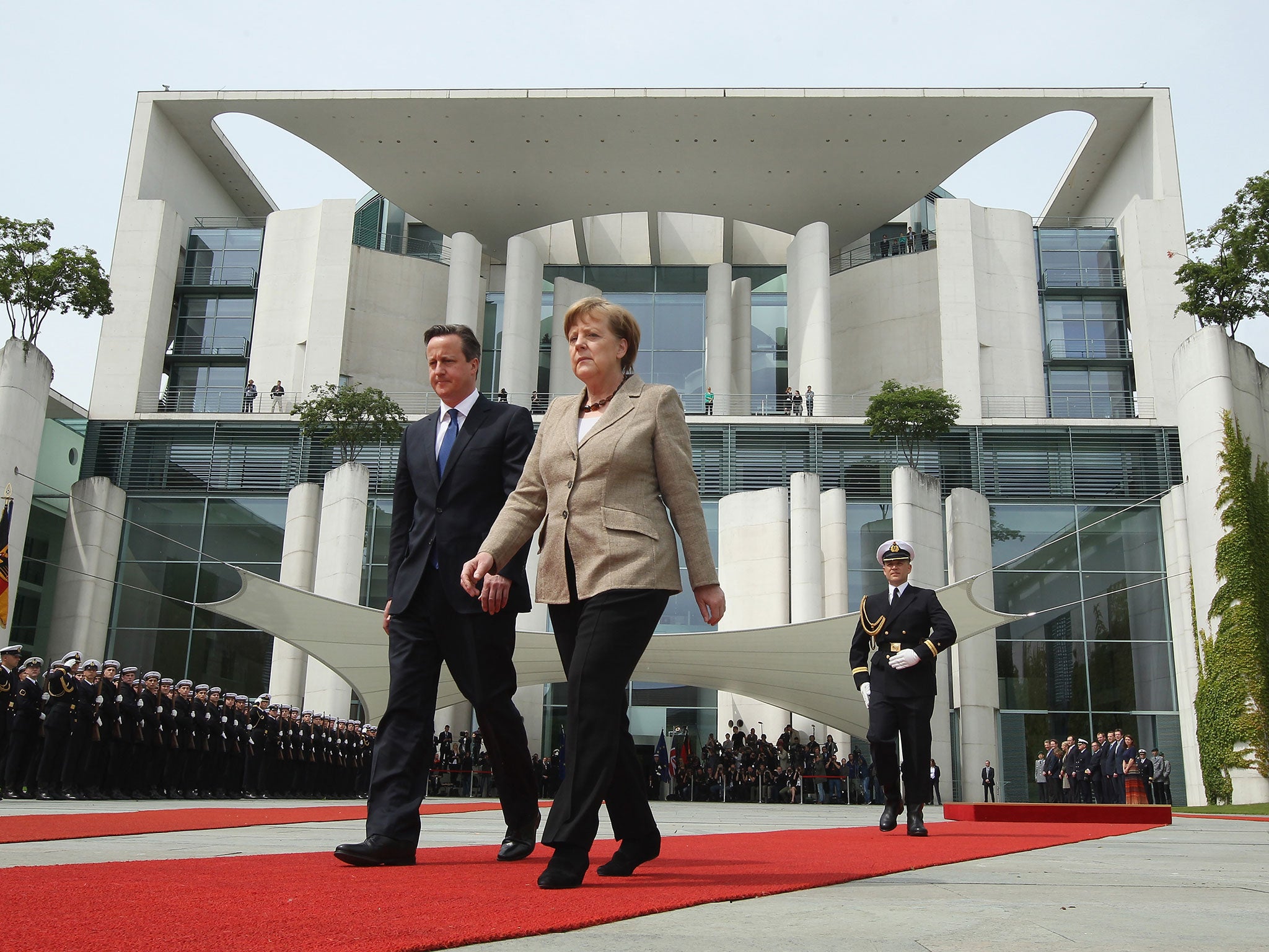 Almost in step, Angela Merkel and David Cameron prepare to review a guard of honour in Berlin yesterday