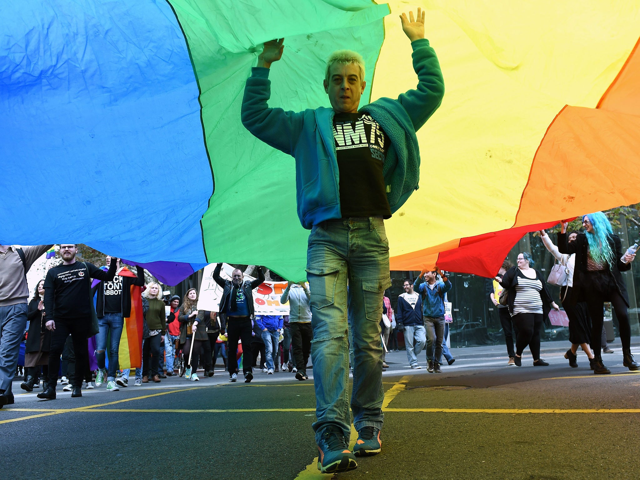 A demonstrator advances through Sydney beneath a rainbow flag