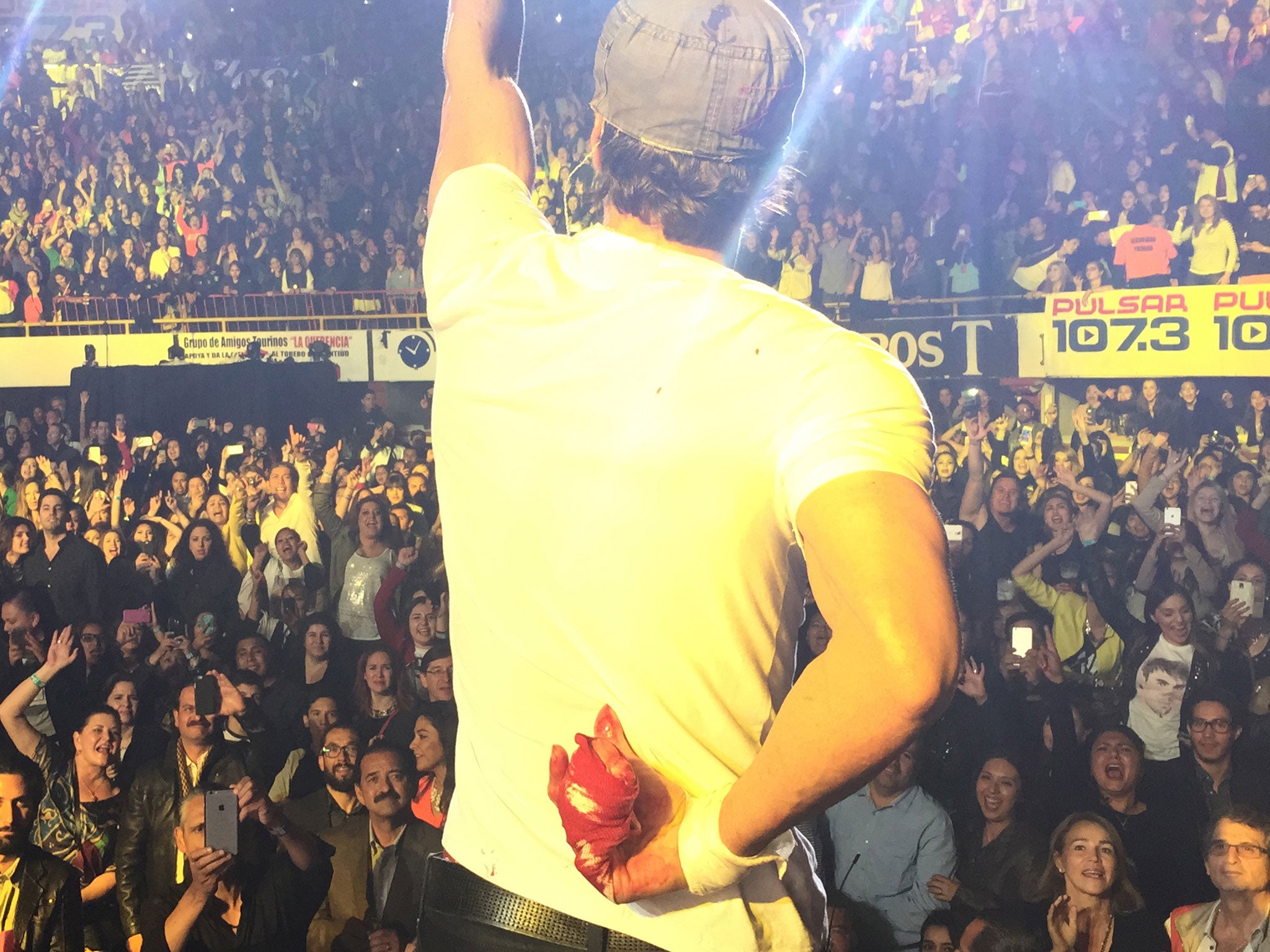 Enrique Iglesias performs while holding his bloodied and bandaged right hand behind his back during a concert in Tijuana, Mexico