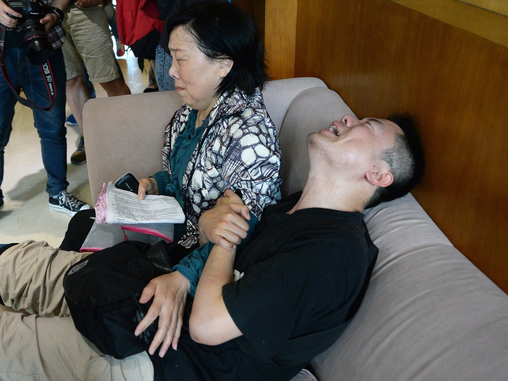 A man, accompanied by his aunt, grieves for his missing parents