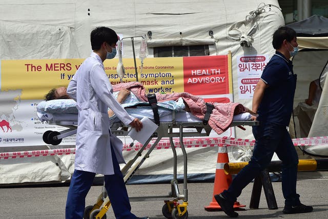 South Korean hospital workers carry transport a man in front of a quarantine tent for suspected MERS cases at the Seoul National University Hospital in Seoul