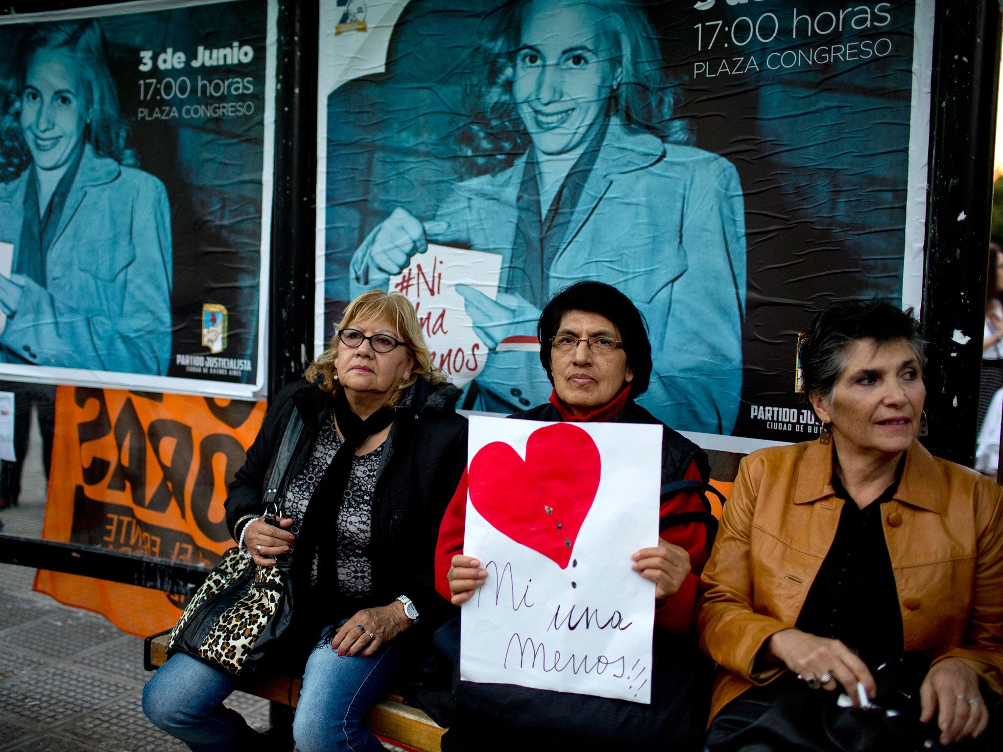 A woman holds a sign that reads in Spanish "Not one less," referring to the murder of women