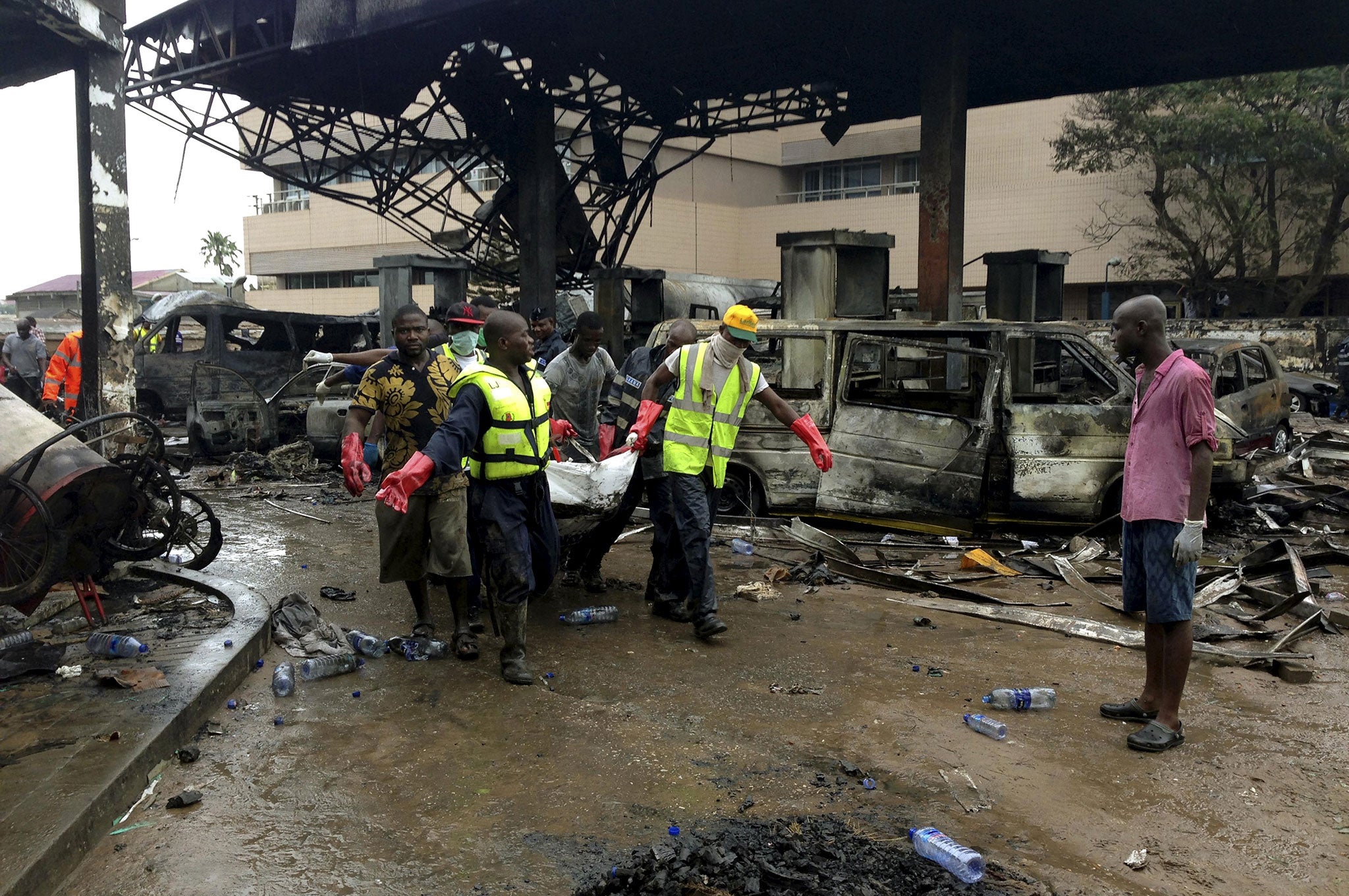 Rescue workers carry a corpse from the remains of a petrol station that exploded overnight killing around 90 people in Accra, Ghana