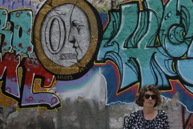 A woman stands in front of graffiti depicting a zero Euro coin in Athens. Fears are growing that a deal will not be reached to repay a first tranche of Greece’s debts to international lenders