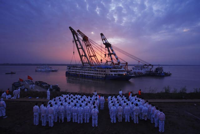Workers watch as the ship is righted on the Yangtze on Friday 