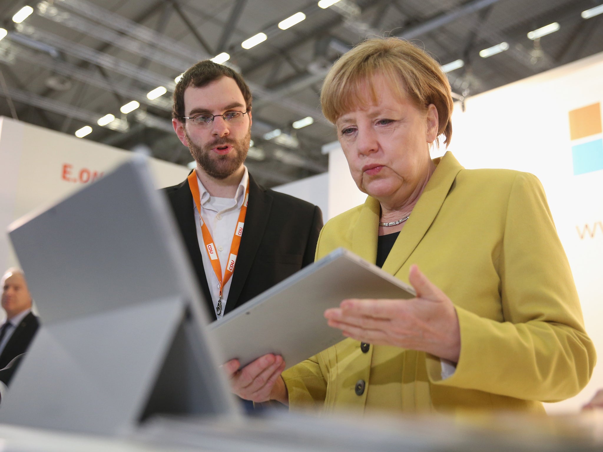 German Chancellor and Chairwoman of the German Christian Democrats (CDU) Angela Merkel looks at a tablet computer at the Microsoft stand while visiting exhibitors at the annual CDU party congress on December 10, 2014 in Cologne, Germany