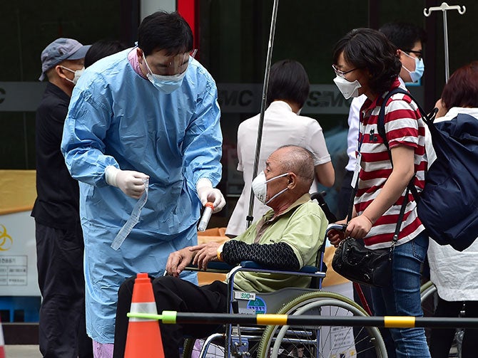 A medical worker from South Korea handles a sample tube from a man suspected of carrying the MERS virus
