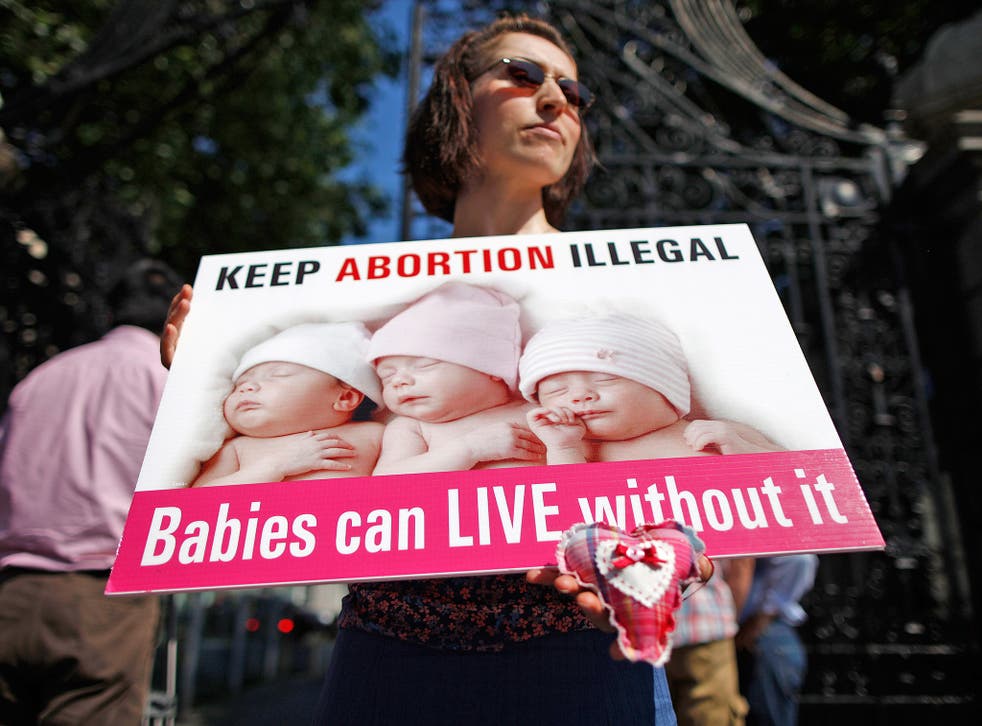 A protester holds an anti-abortion placard in front of the gates of the Irish Parliament in Dublin, in 2013
