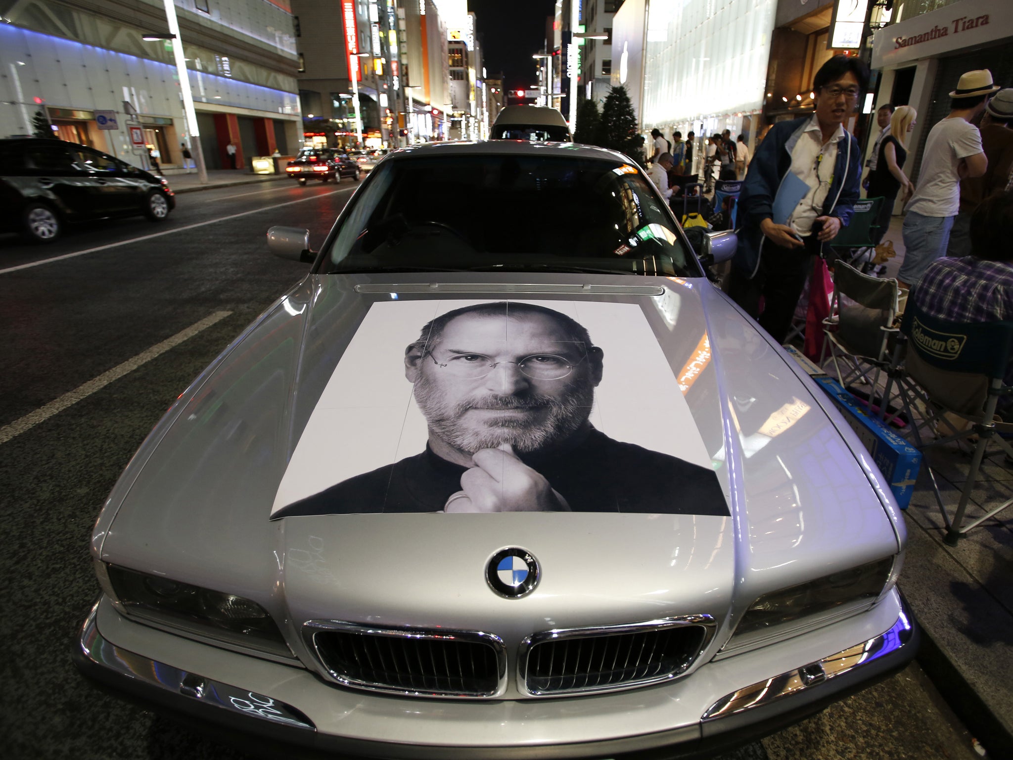 A portrait of Apple's co-founder Steve Jobs is seen on a BMW car as people wait for the release of Apple's new iPhone 5S and 5C, near the Apple Store at Tokyo's Ginza shopping district September 19, 2013, a day before the phones go on sale