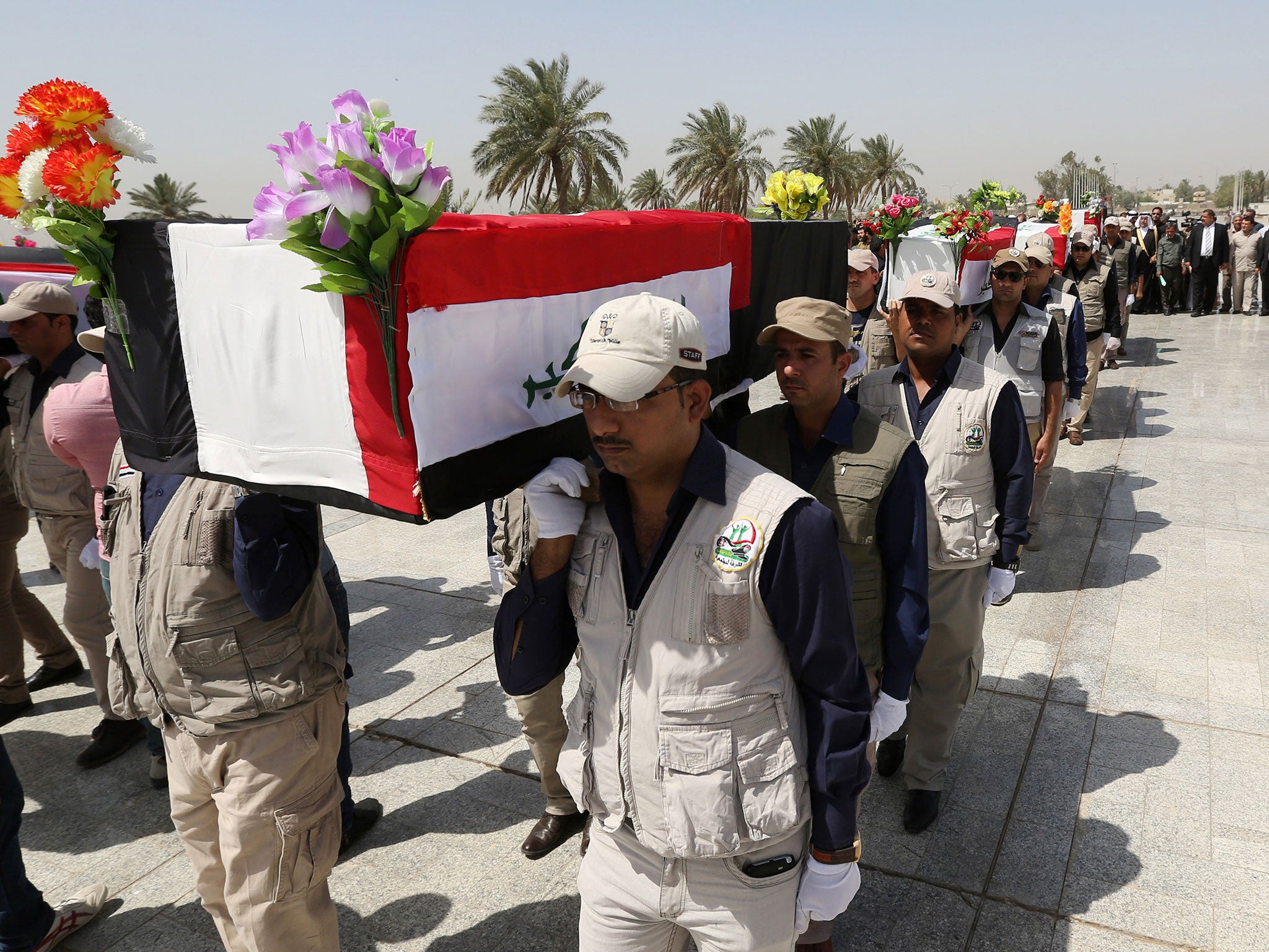 Mourners carry flag-draped coffins at a symbolic funeral for Iraqi soldiers killed by Isis when they overran Camp Speicher military base. 8 June 2015