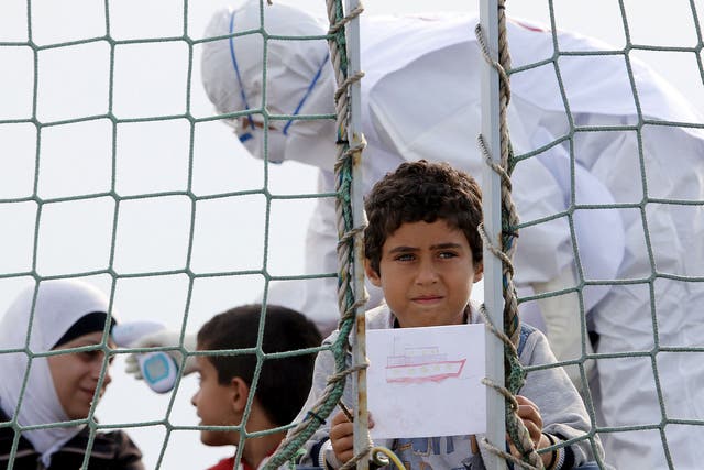 A Syrian child holds a drawing as he waits to disembark from Belgian Navy vessel Godetia at the Augusta port, Italy. Around 250 migrants from Syria arrived at the Sicilian harbour from a Damascus refugee camp