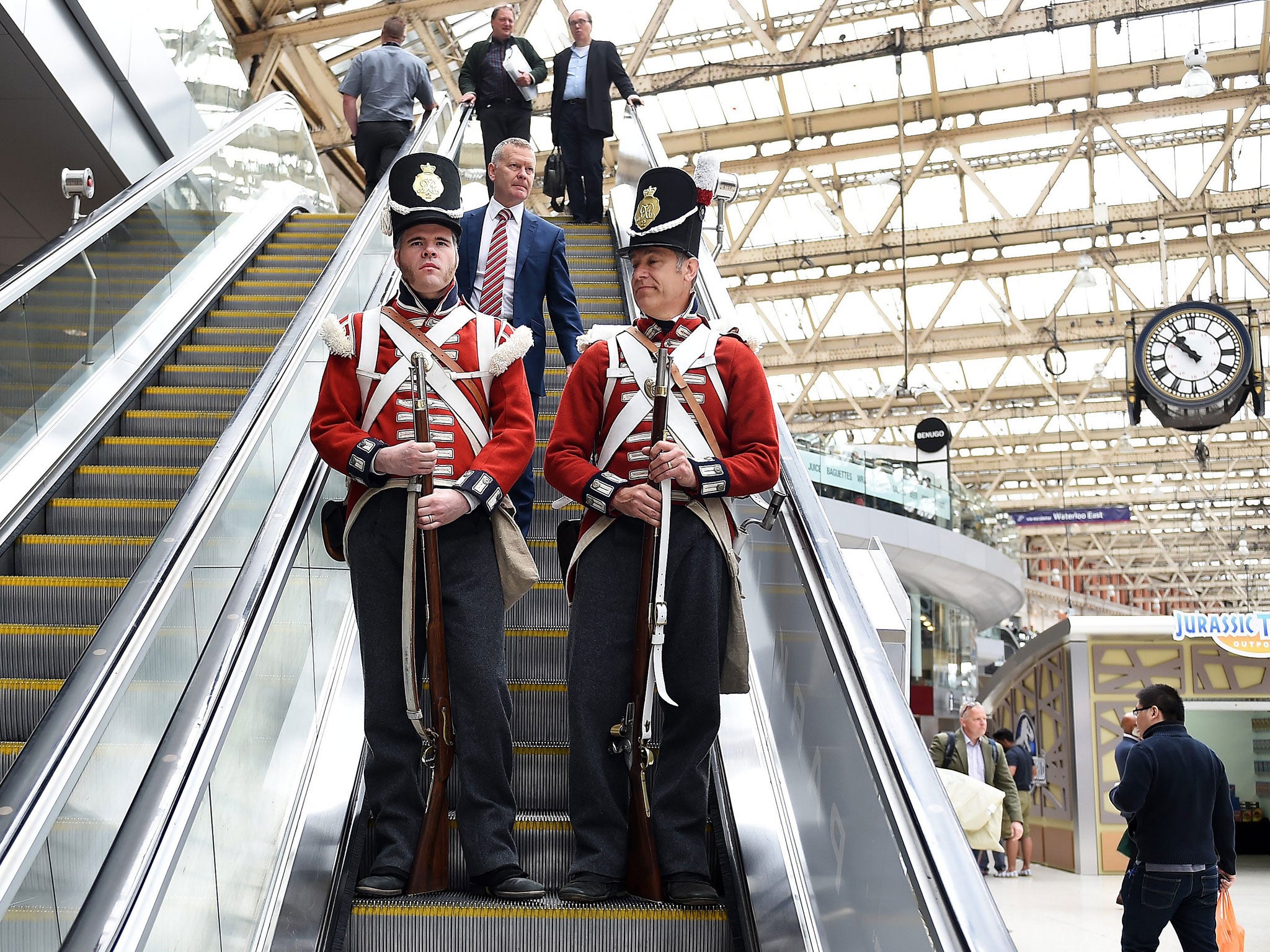 Men dressed as soldiers from the Grenadier Company during the Waterloo Campaign ride a escalator at Waterloo Station in London.