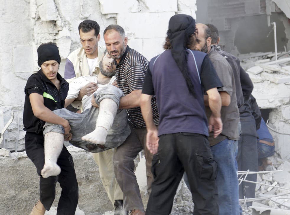 Residents carry an injured man at a site damaged by what activists said was a barrel bomb dropped by forces loyal to Syria's president Bashar Al-Assad in Maarat Al-Nouman, south of Idlib