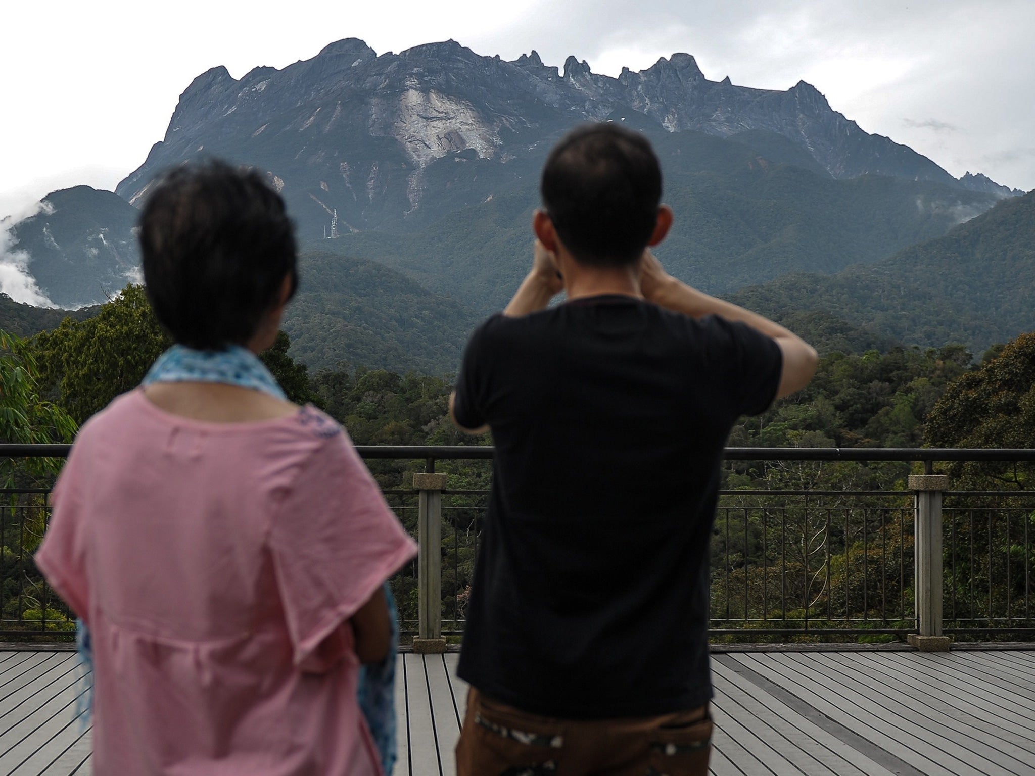 A tourist takes pictures of Malaysia's Mount Kinabalu