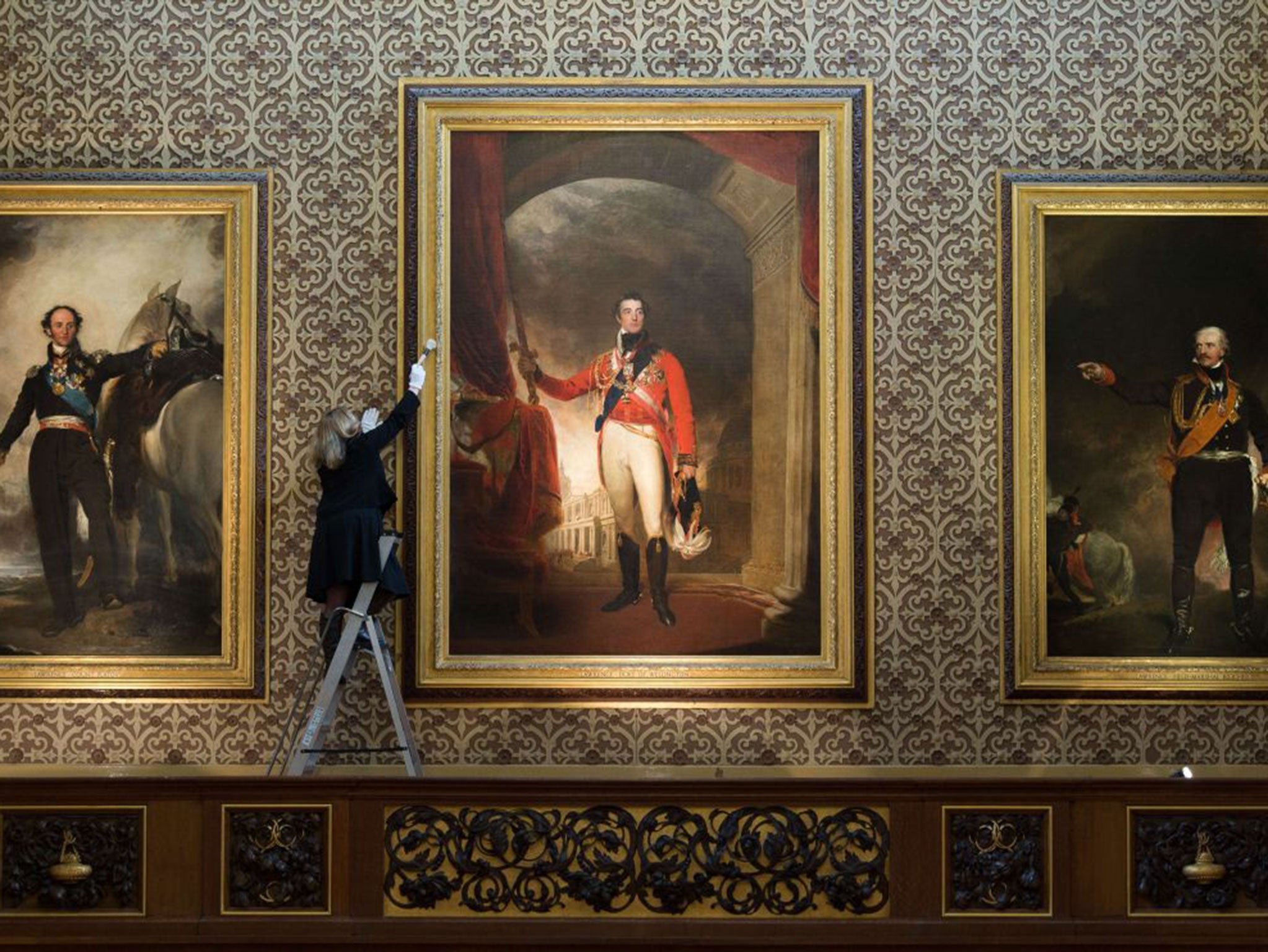 A woman dusts the frame of a painting of Arthur Wellesley, Duke of Wellington by Thomas Lawrence