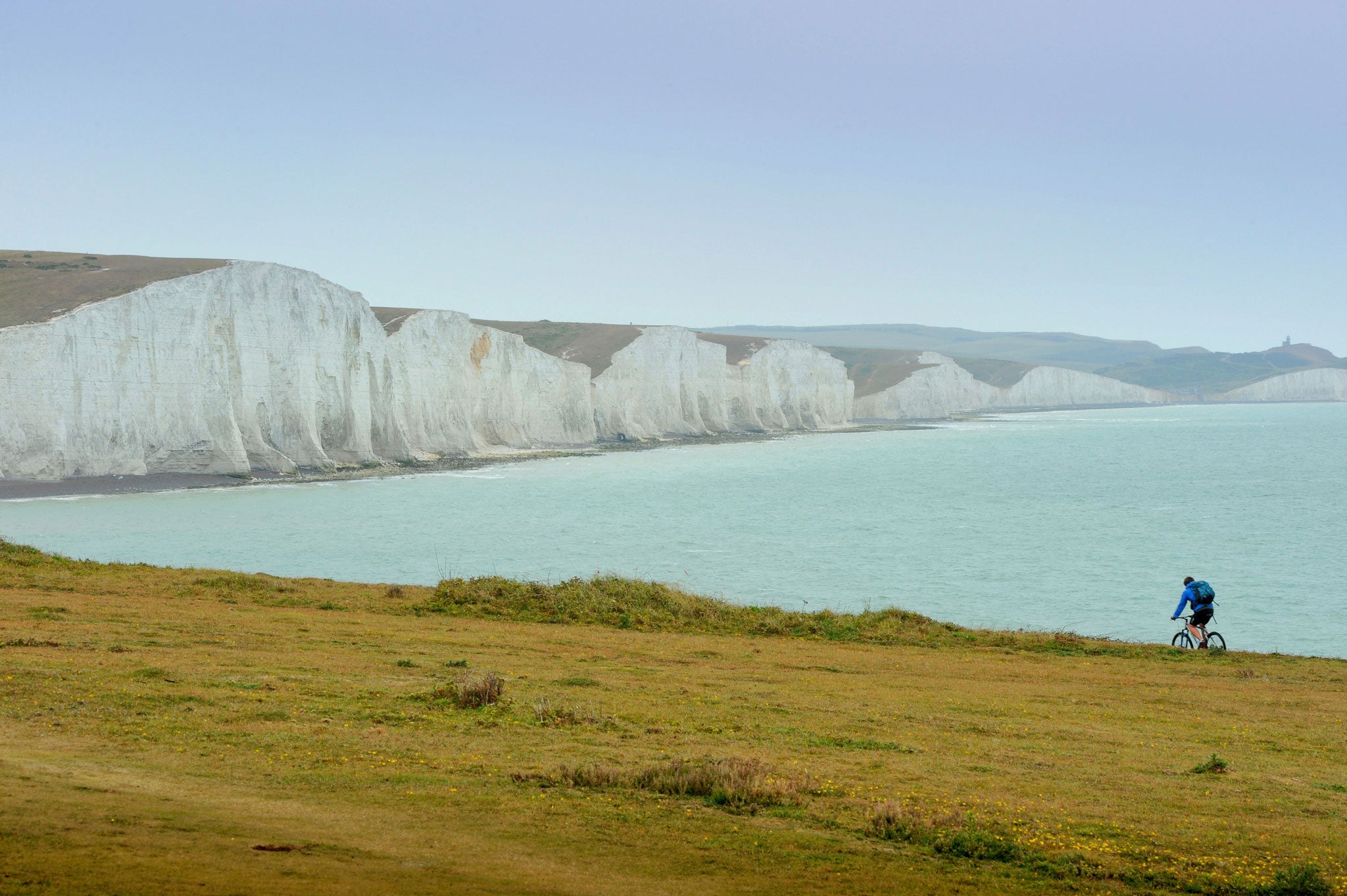 A cyclist rides past the dramatic Seven Sisters cliffs in East Sussex