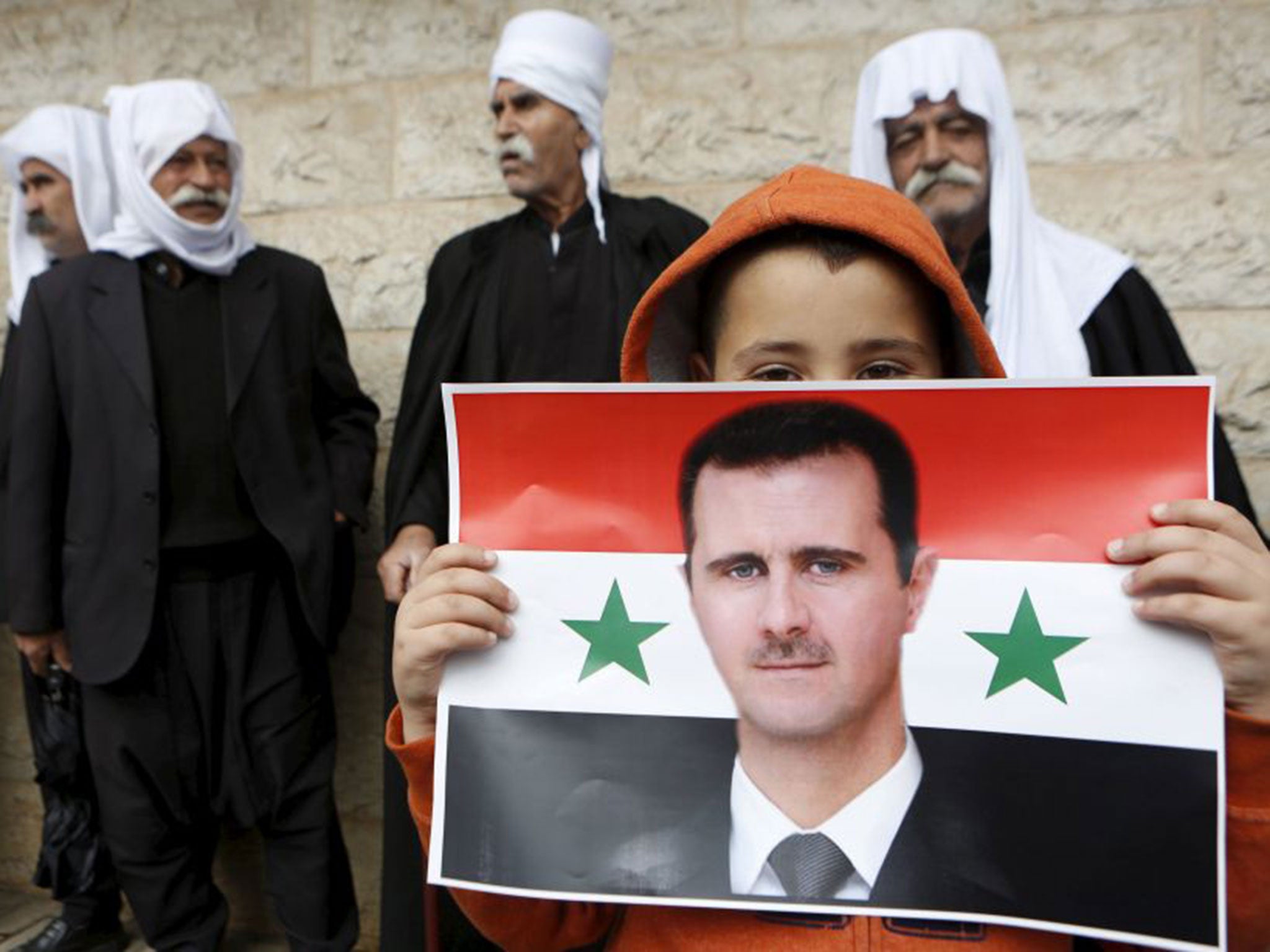 A boy from the Druze community, threatened by militants, holding a Syrian flag with the image of Bashar al-Assad during a rally marking Independence Day in a village on the Golan Heights