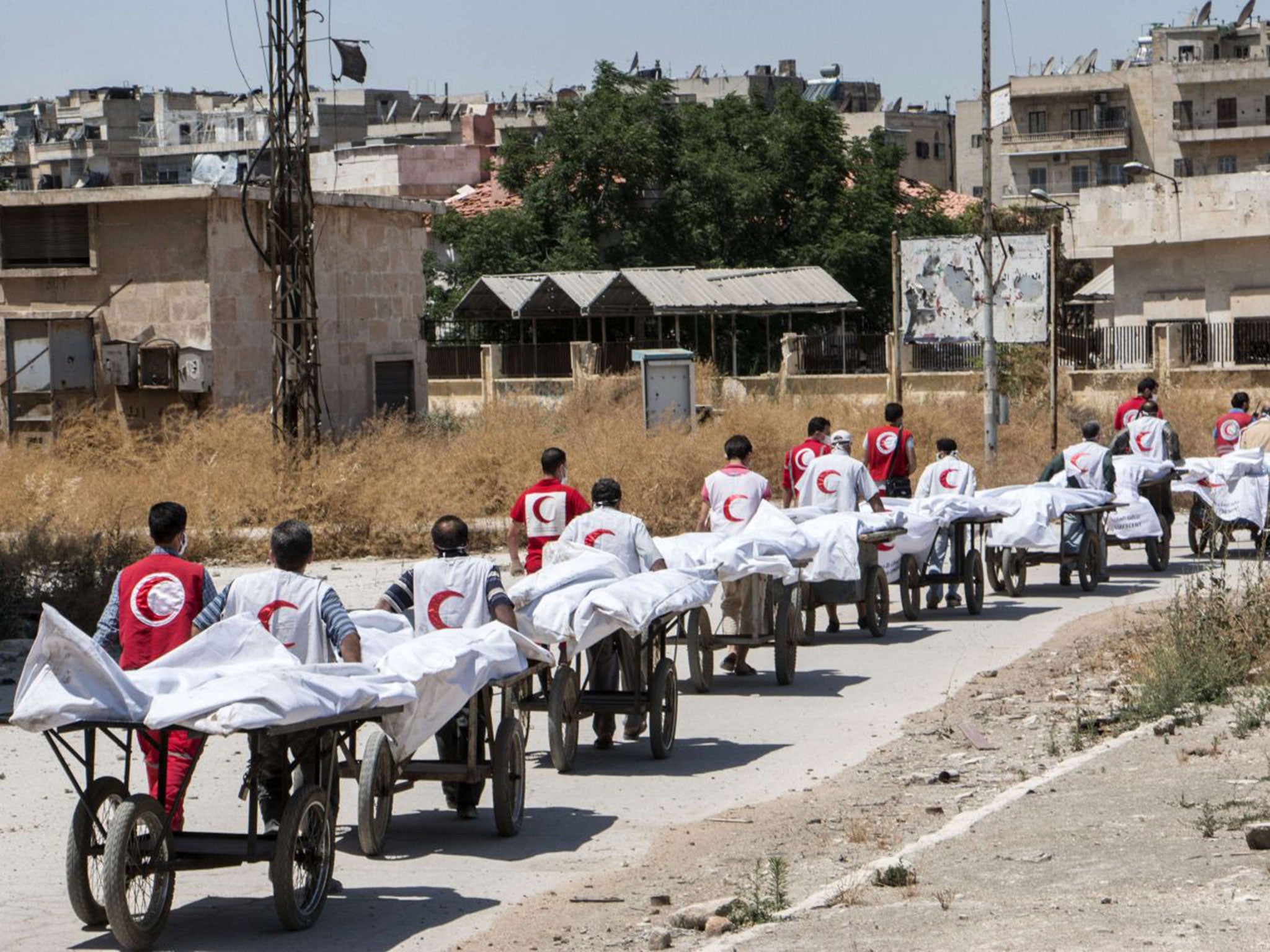 Members of the Syrian Red Crescent transport the bodies of reported regime fighters from rebel-held area into regime-held area