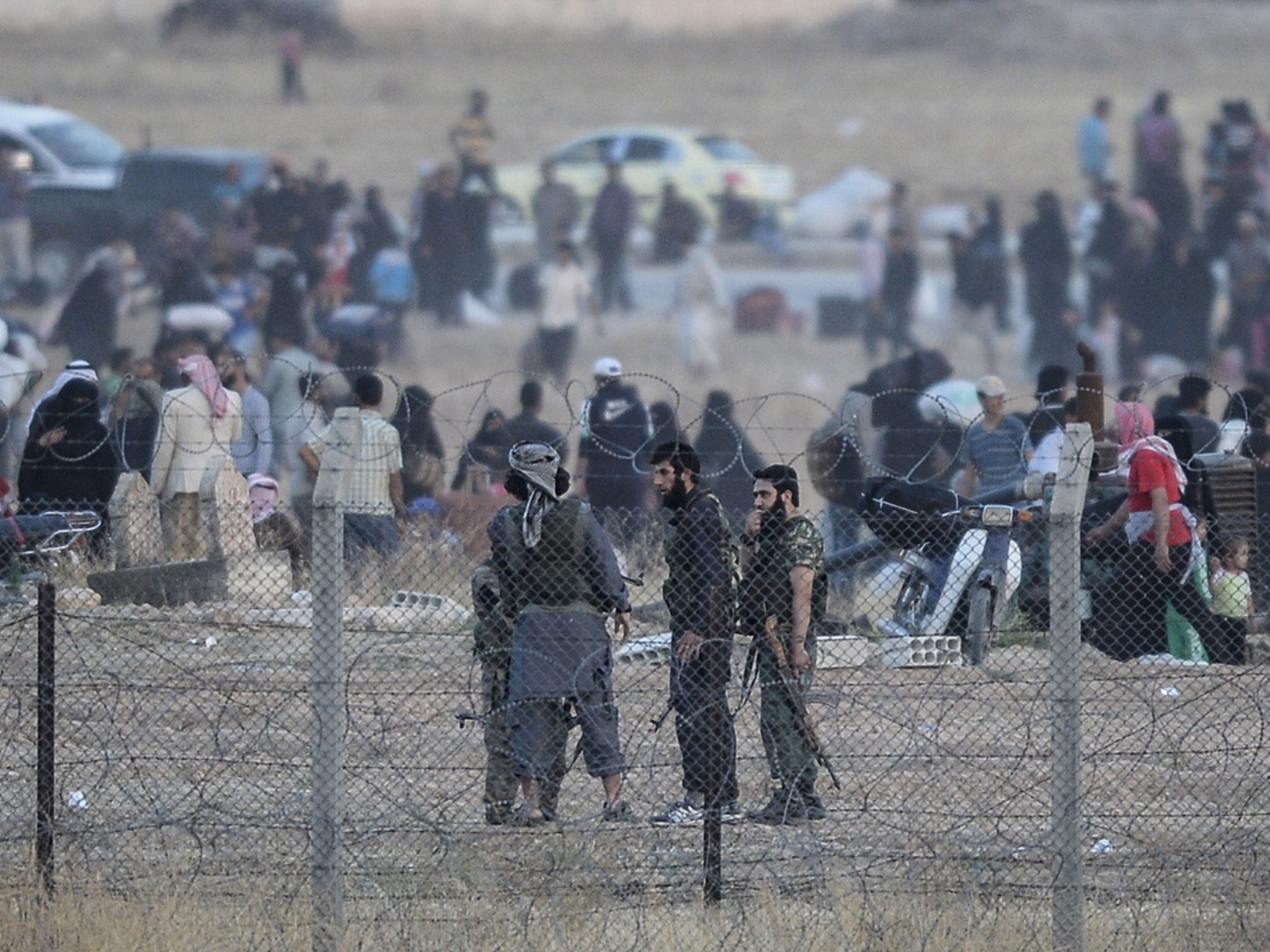 Men believed to be members of the Isis speak as people carry belongings back to the city centre of the Syrian town of Tal Abyad, as seen from Turkey (credit:Bulent Kilic/ AFP/ Getty).