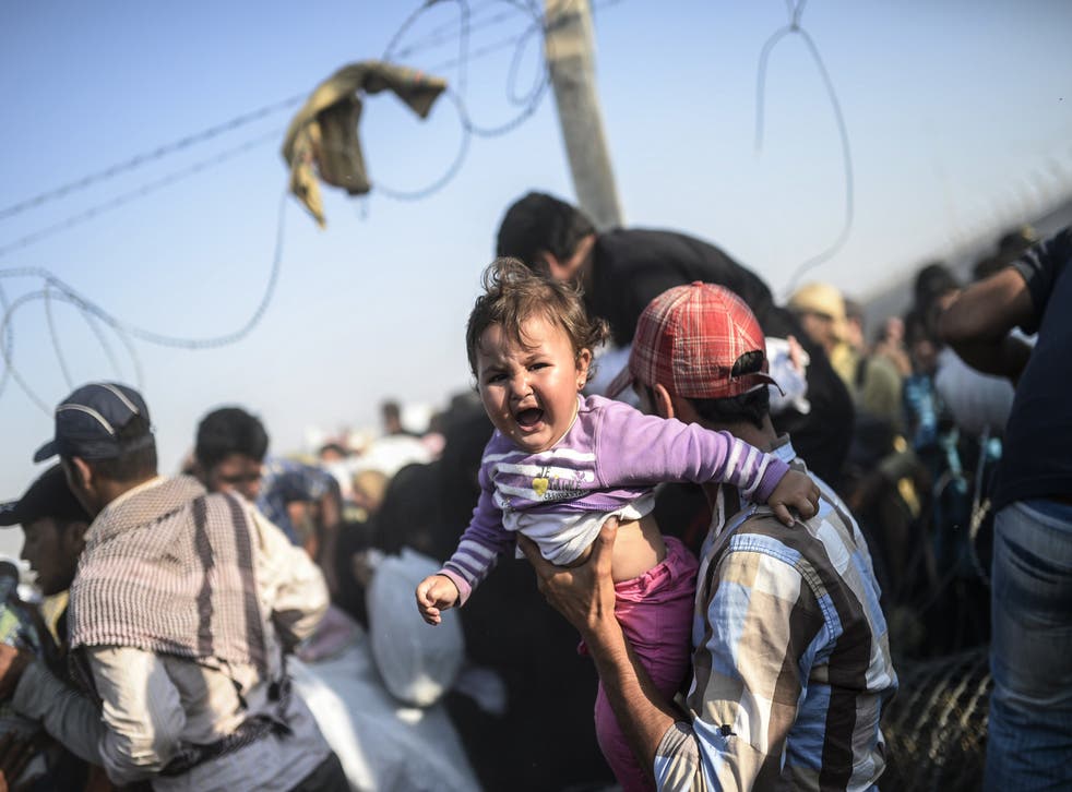 A Turkish man carries his child across the border (Photo: BULENT KILIC/AFP/Getty Images)