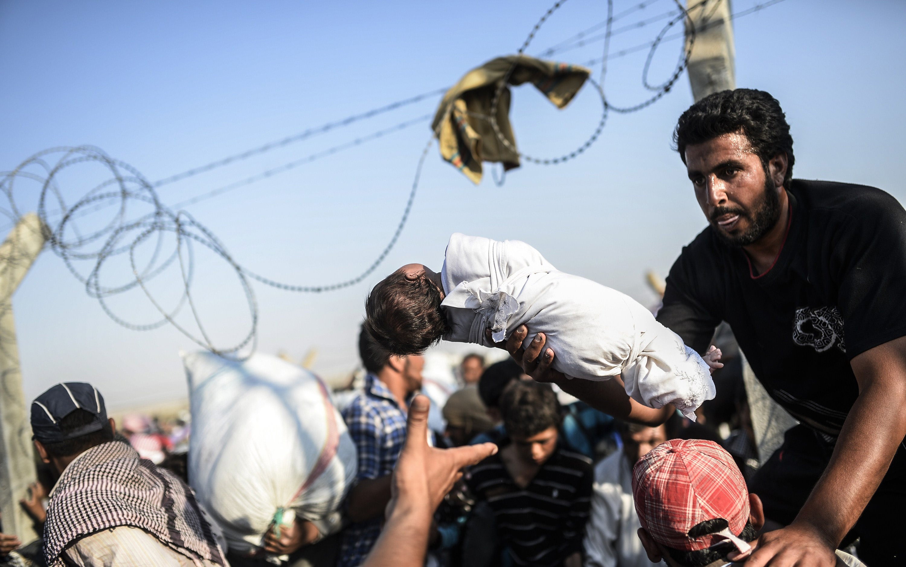 A Syrian man passes his newborn child over the border (Photo: BULENT KILIC/AFP/Getty Images)