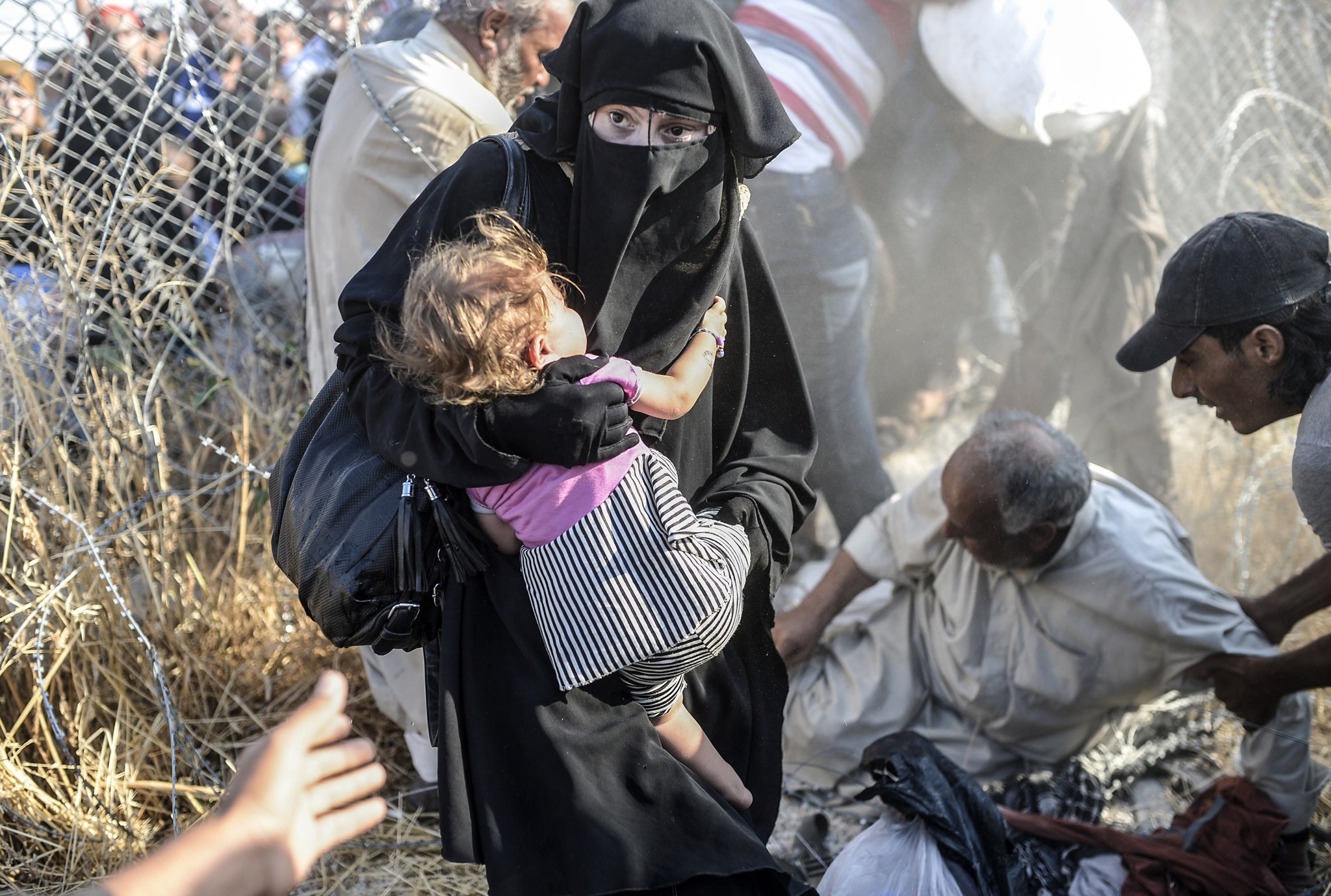 A woman clutches her child as she enters Turkish territory (Photo: BULENT KILIC/AFP/Getty Images)