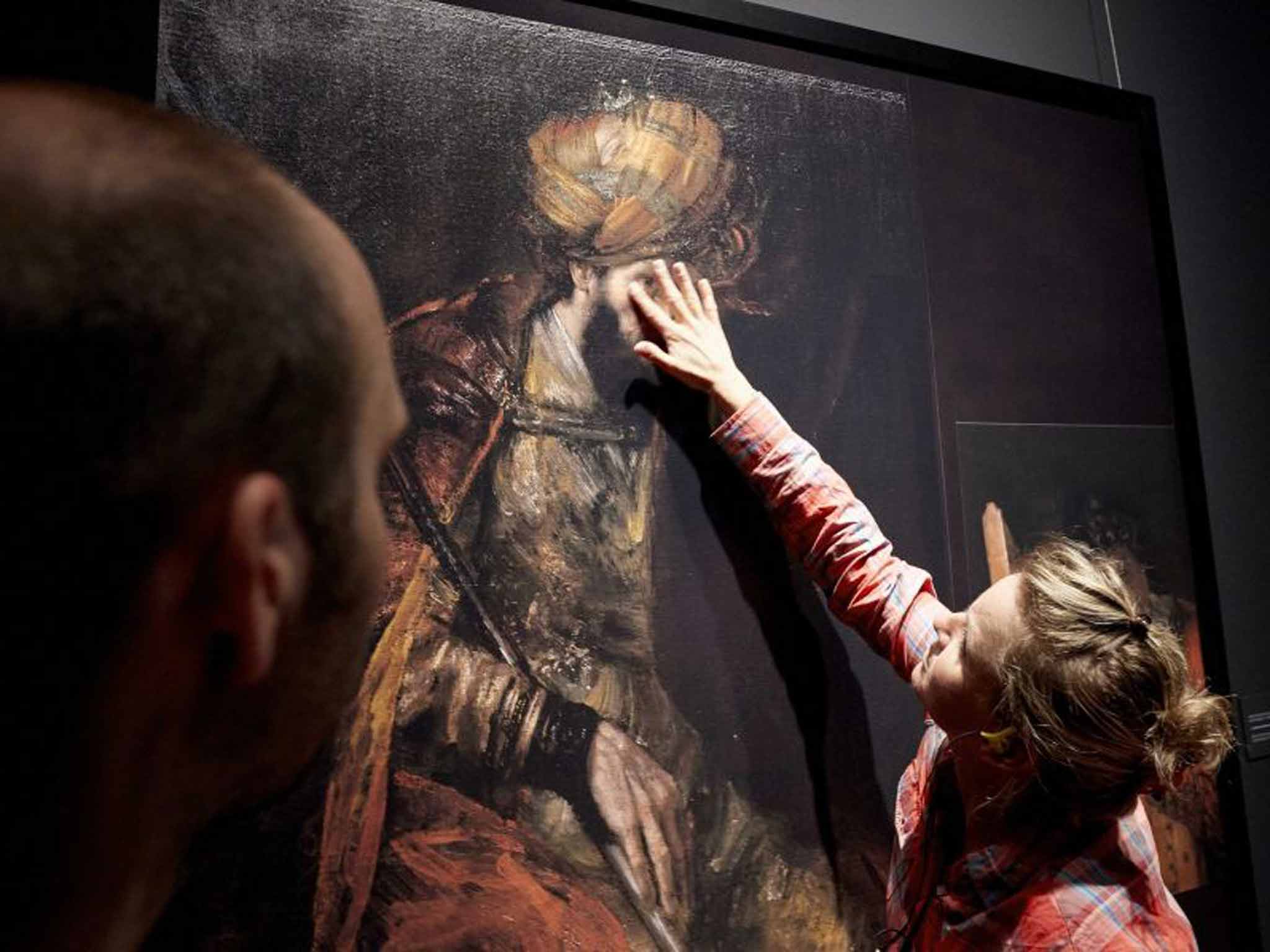 A member of the Mauritshuis museum's staff touches the piece