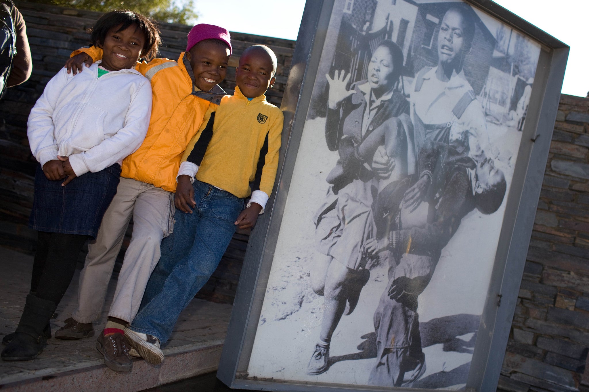 South African children pose next to the famous photo of 13-year-old Hector Pieterson being carried by students at Hector Pieterson Museum in Soweto on June 16, 2010.