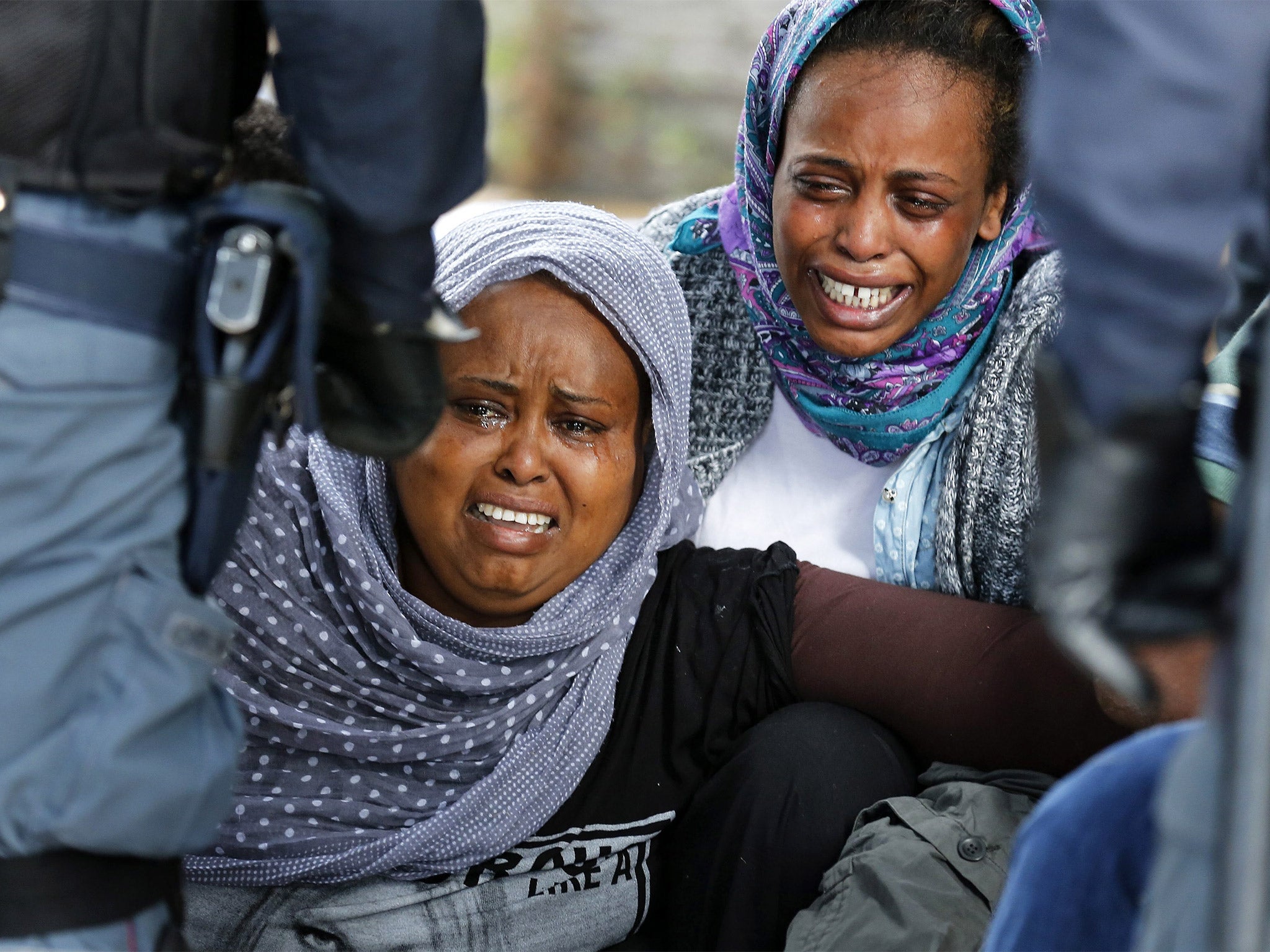 African migrants cry as Italian police stop them from crossing the border into France in Ventimiglia, Italy