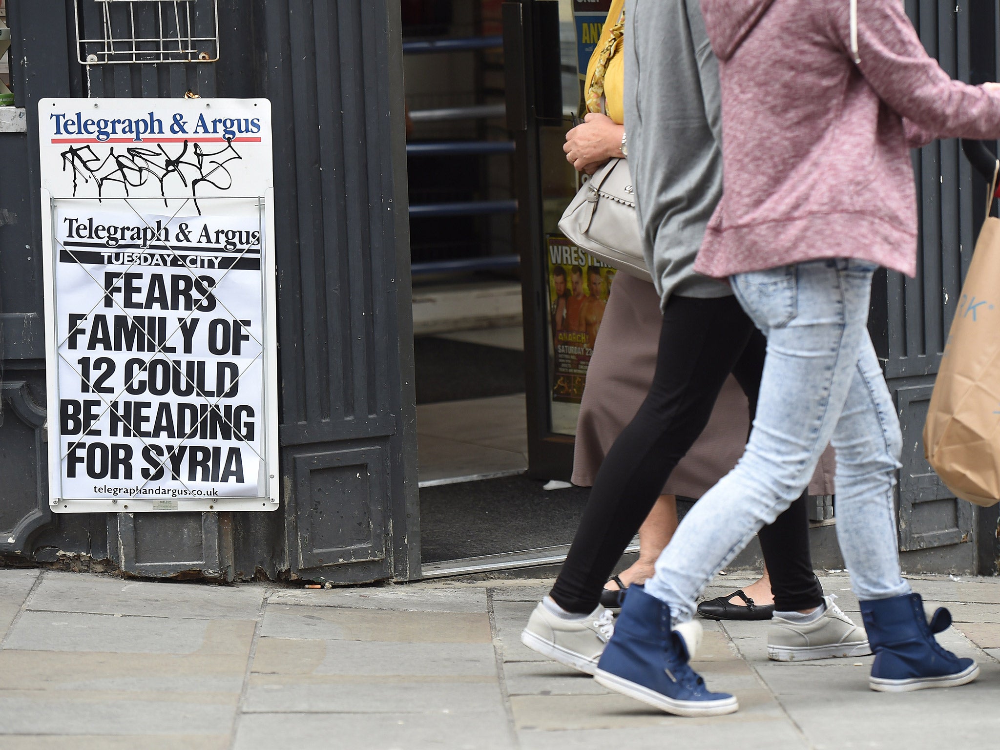 Pedestrians walk past a newsagents displaying a local paper headline on a notice board referring to fears regarding a missing family of 12 in Bradford