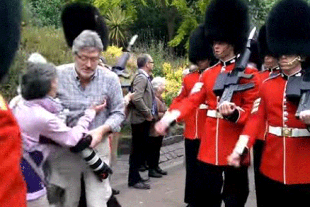 Footage has emerged of the moment a man with a camera is barged into by the Queen's Guards as he stands in their way