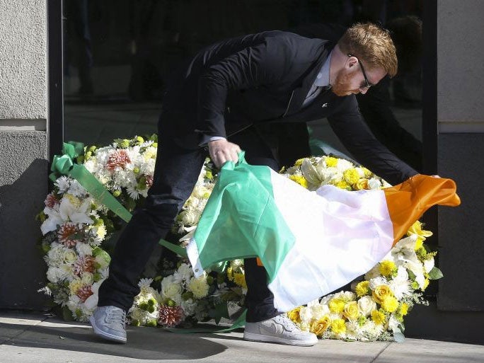 Neil Sands, president of a local Irish network, lays and Irish flag on wreaths left with tributes near the scene of the tragedy