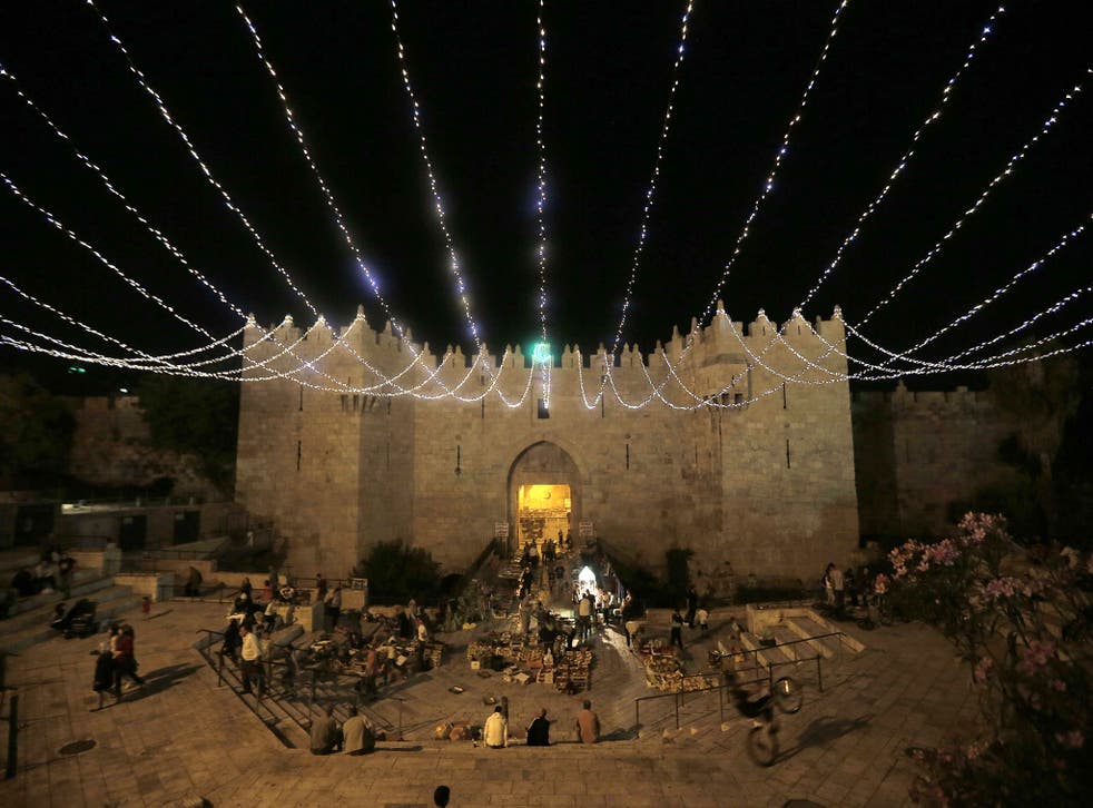 People walk under lights decorating Damascus Gate outside the old city of Jerusalem, as Muslims around the world prepare for the announcement of the fasting month of Ramadan 