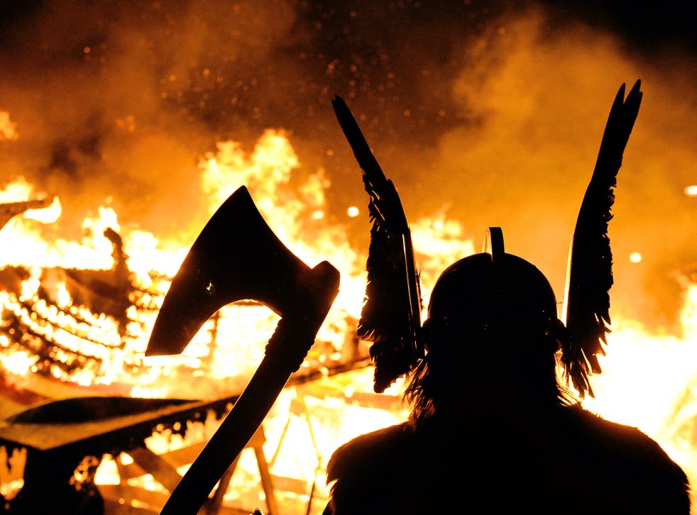 A man in viking costume is silhoutted by a burning longship during the annual Up Helly Aa Festival in Lerwick, Shetland Islands