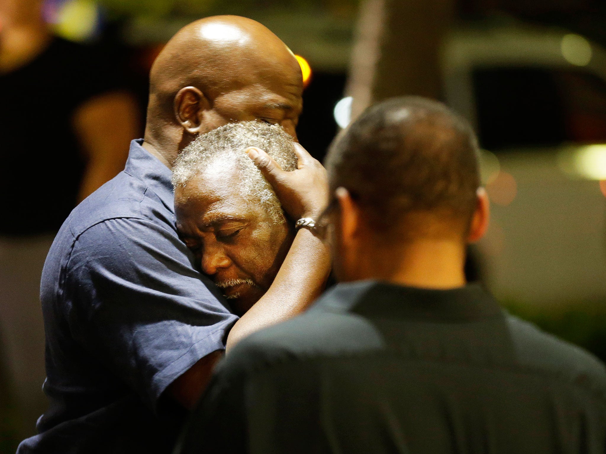 Worshippers embrace following a group prayer across the street from the scene of a shooting