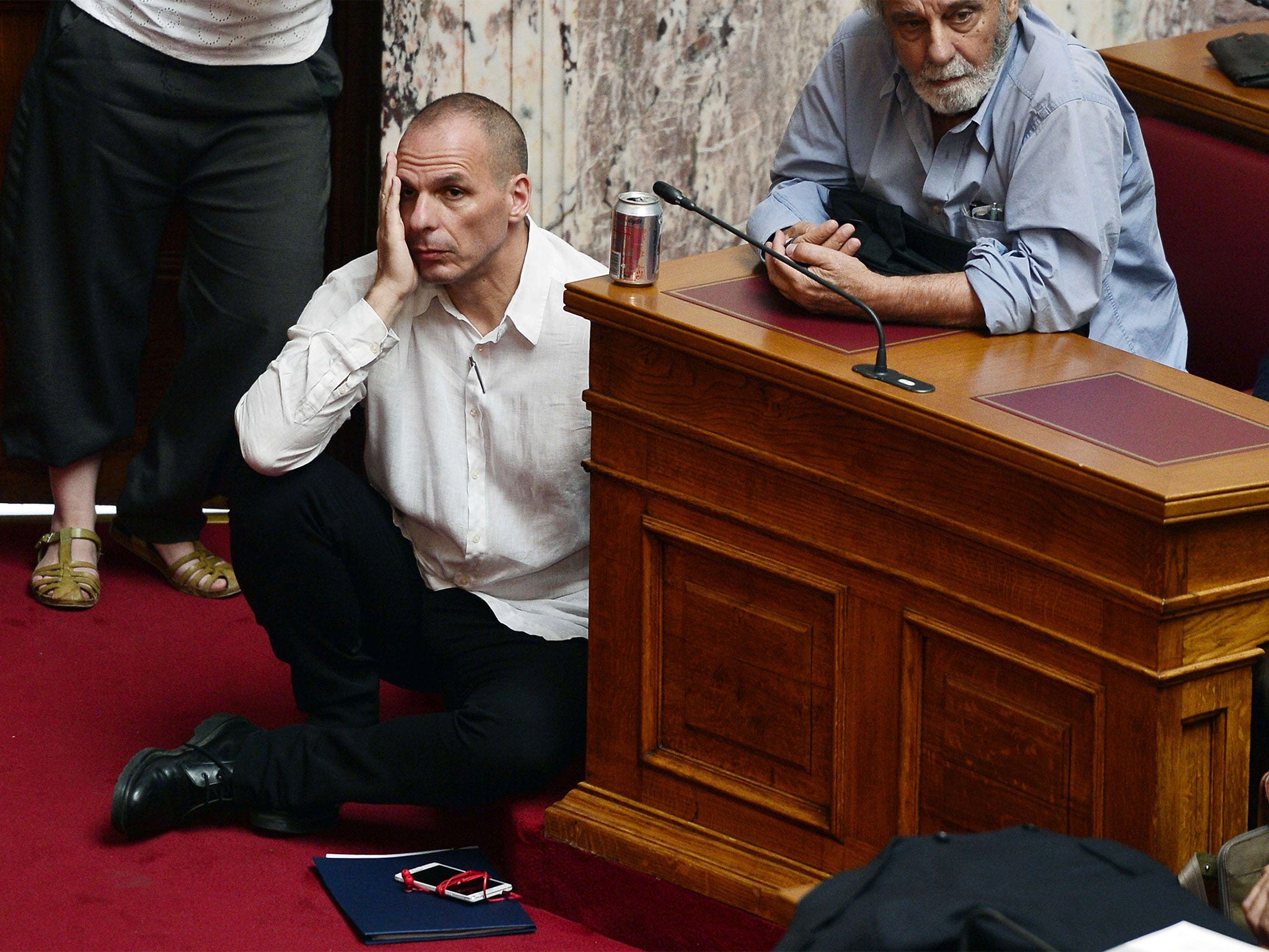 Greek Finance Minister Yianis Varoufakis (L) listens to the Prime Minister Alexis Tsipras addressing his MP's and ministers at the Greek Parliament