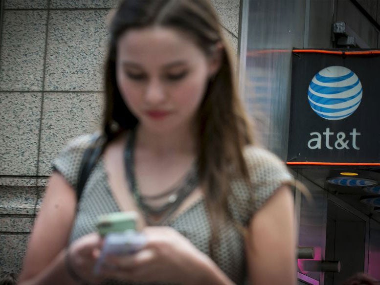 A woman uses her phone outside the AT&T store in New York's Times Square, June 17, 2015. The U.S. Federal Communications Commission on Wednesday proposed a $100 million fine for AT&T Inc, accusing the No. 2 wireless carrier of misleading customers who pai