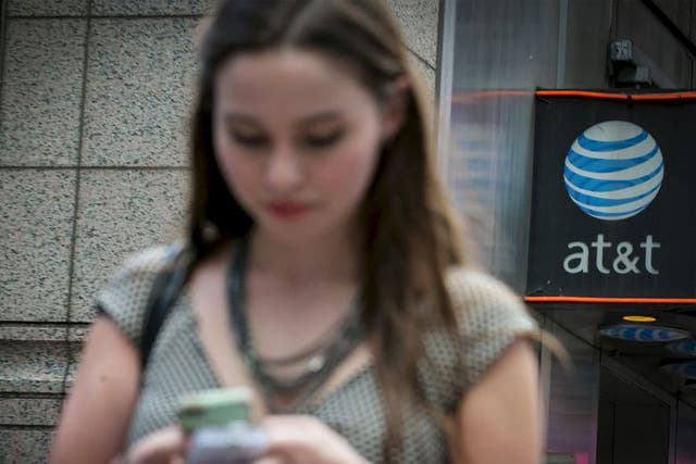 A woman uses her phone outside the AT&T store in New York's Times Square, June 17, 2015. The U.S. Federal Communications Commission on Wednesday proposed a $100 million fine for AT&T Inc, accusing the No. 2 wireless carrier of misleading customers who pai