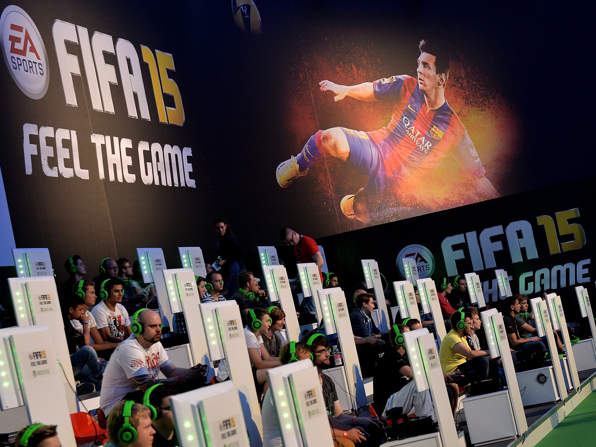 Visitors try out the game 'FIFA 15' at the EA Sports stand at the 2014 Gamescom gaming trade fair on August 14, 2014 in Cologne, Germany