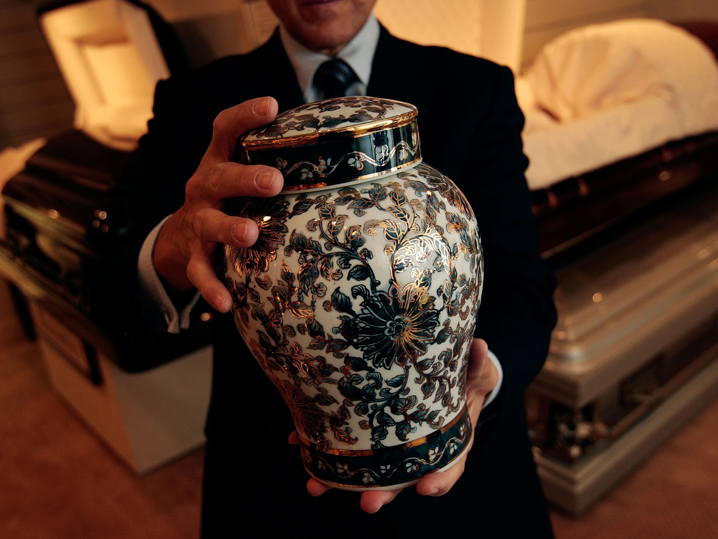 A funeral director holds an urn in his New York funeral home
