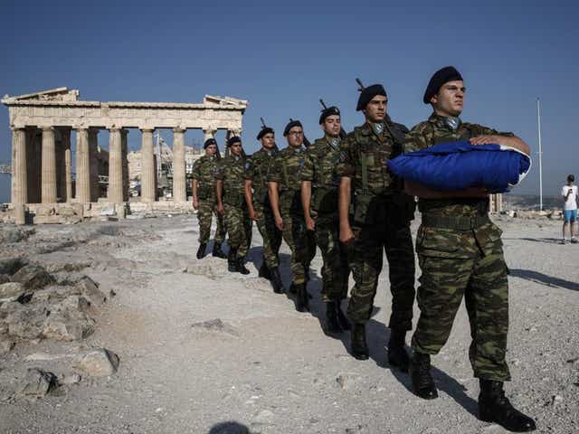 Soldiers carry the Greek flag to be hoisted at the Parthenon yesterday as the country lives through major uncertainty over its future