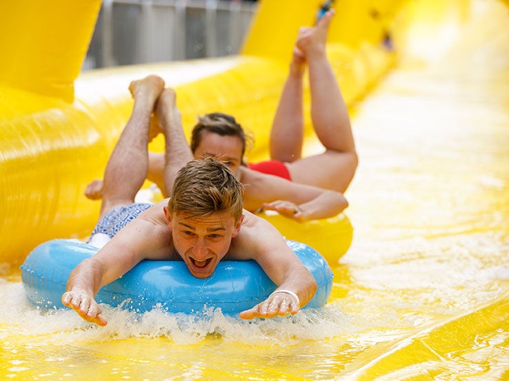 Londoners take turns down King's Cross water slide | The Independent