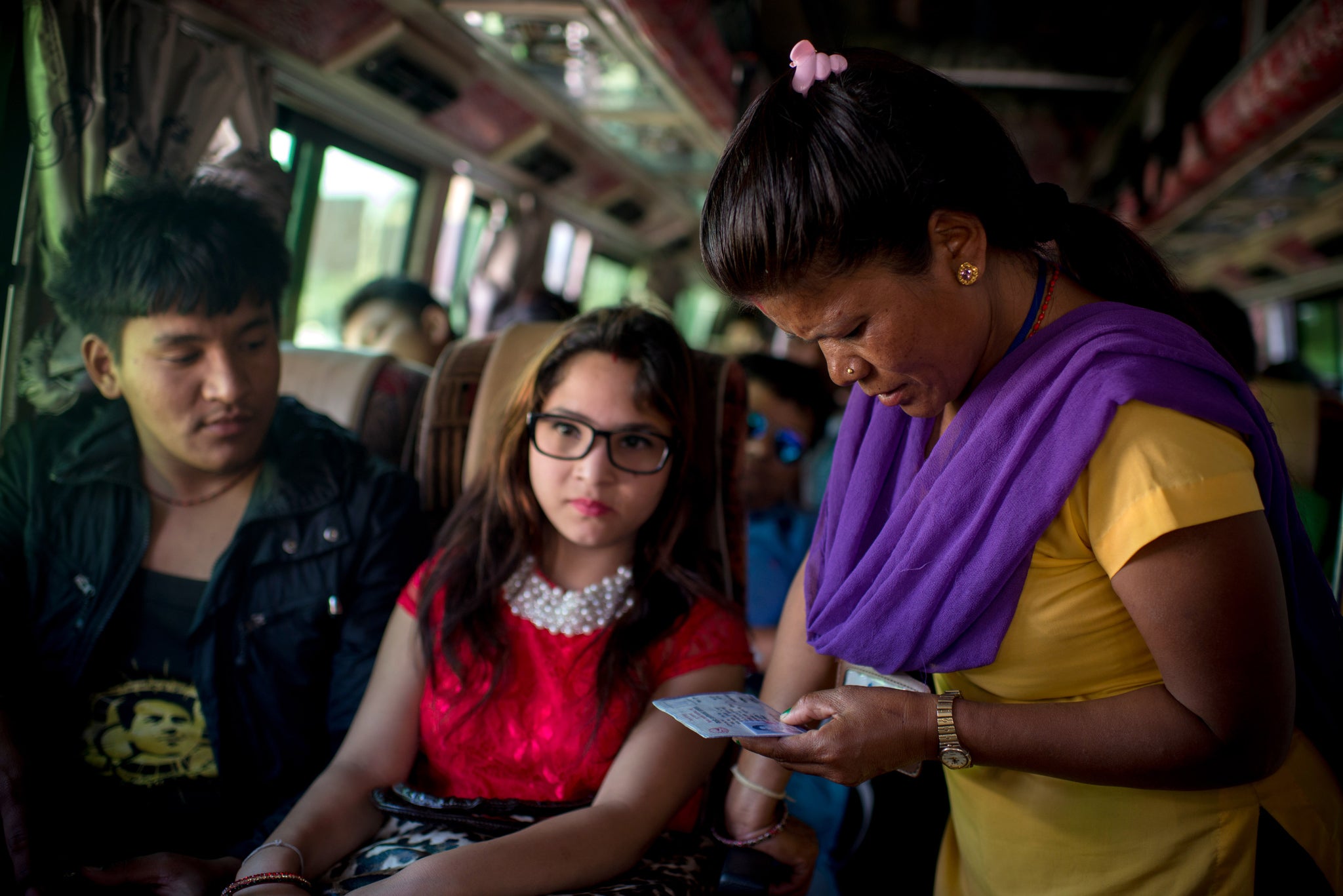 A worker for anti-trafficking organisation Mati Nepal checks a girl's ID on a bus to India, trying to ensure she is not being trafficked.