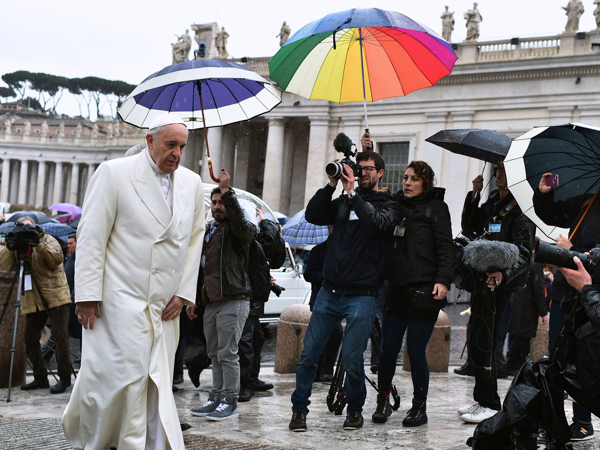 Pope Francis arrives under heavy rain, for his weekly general audience in St Peter's square at the Vatican on March 25, 2015