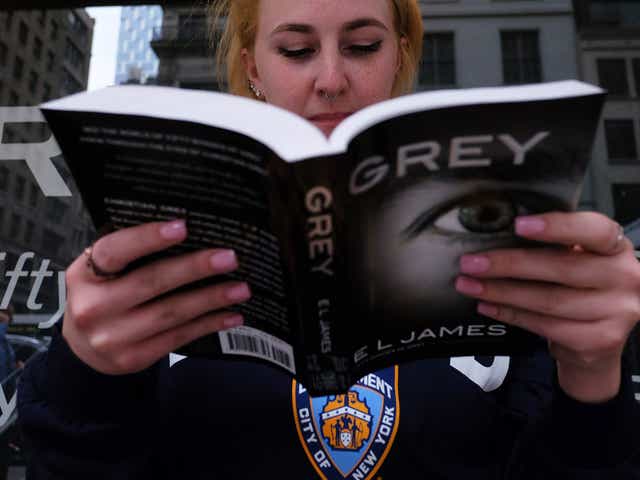 A woman reads a copy of E.L James's new book 'Grey: Fifty Shades of Grey as Told by Christian' as she waits in a line to get the book signed by the author at the Barnes and Noble store on Fifth Avenue in New York