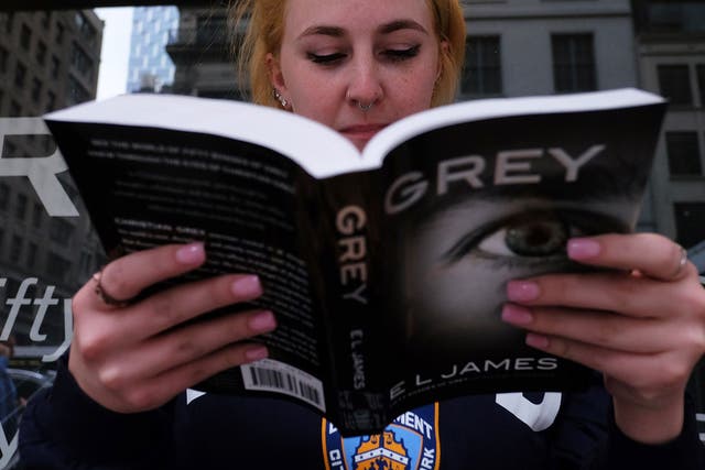 A woman reads a copy of E.L James's new book 'Grey: Fifty Shades of Grey as Told by Christian' as she waits in a line to get the book signed by the author at the Barnes and Noble store on Fifth Avenue in New York