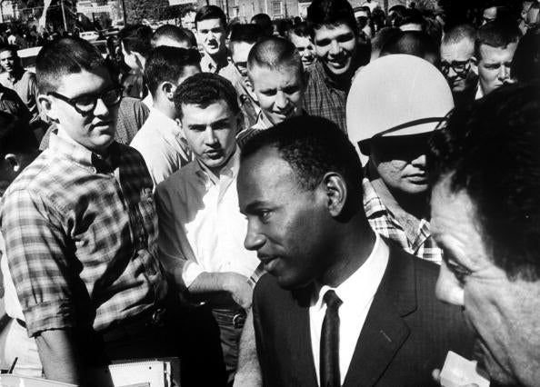 James Meredith is accompanied by two US Marshalls in 1962 as white students jeer after he registered for entry at Ole Miss